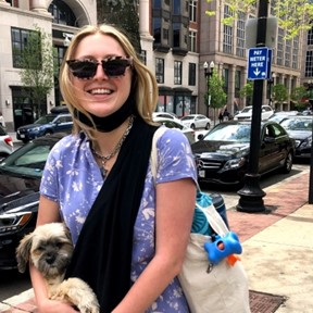 Karleigh Corliss holding a small dog on a city street